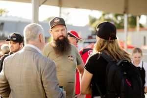 People in casual and business attire engage in conversation at an outdoor gathering.