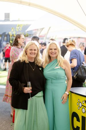Two people wearing mint green outfits pose together at an outdoor festival or event.