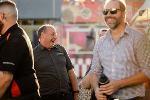 A group of people sharing a laugh and conversing outdoors at a casual gathering.