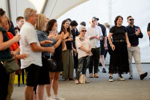 Crowd of attendees lined up along a walkway at an outdoor social gathering.