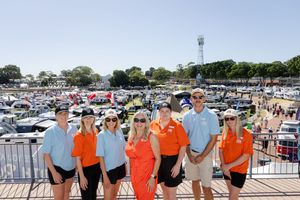 Group photo of attendees standing together at a marina with boats in the background.