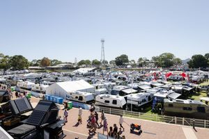 Aerial view of boats, RVs and crowd gathering at a large outdoor marina show or event.