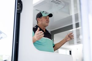 Person working inside food service window at outdoor event.