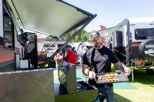 Food vendor preparing food at an outdoor market stand with equipment and serving counter visible.