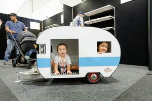 A decorative miniature caravan display featuring a blue and white retro-style design at an exhibition.