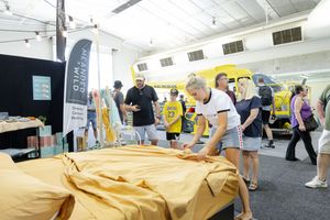 People explore vendor displays at an indoor retail event with yellow and white exhibit booths.