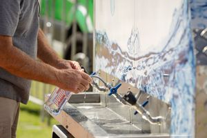Person pouring water into multiple sampling cups at tasting station.