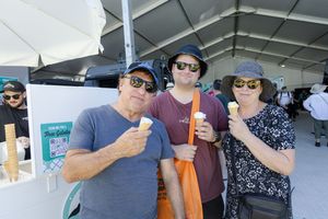 People enjoying drinks under a tent canopy at an outdoor event.