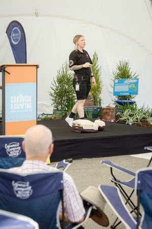 Professional demonstrating technique at a presentation with medical training equipment on stage.