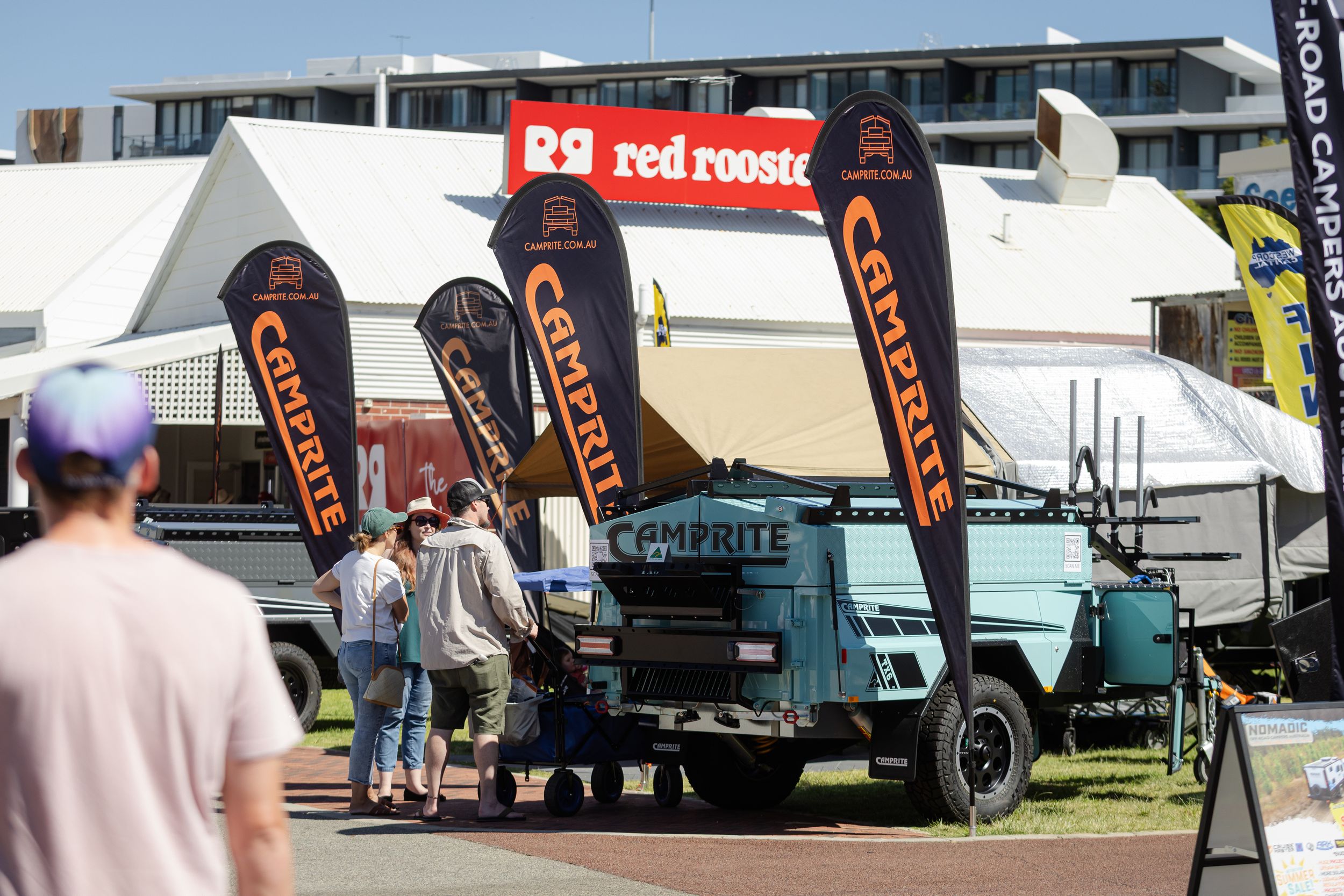 Black promotional feather flags and vintage trucks on display at an outdoor event.