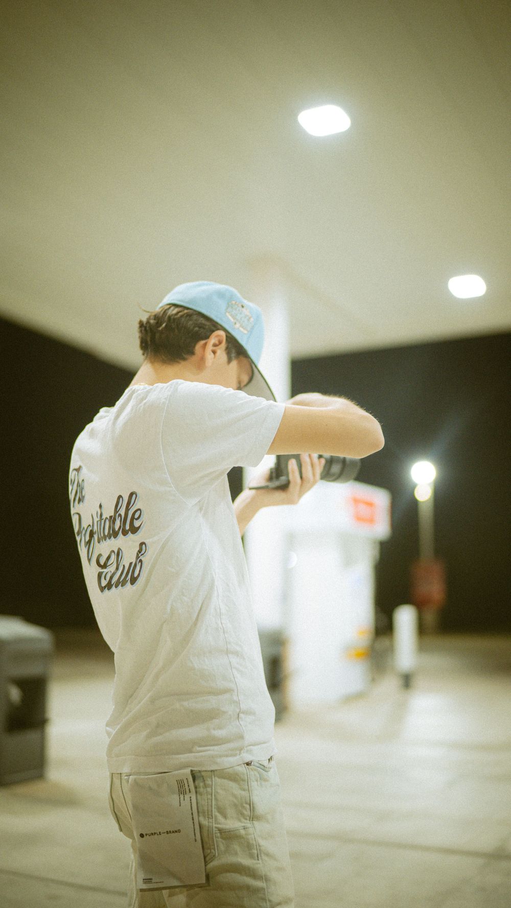 Person wearing a white t-shirt and hat practices shooting at an indoor gun range.