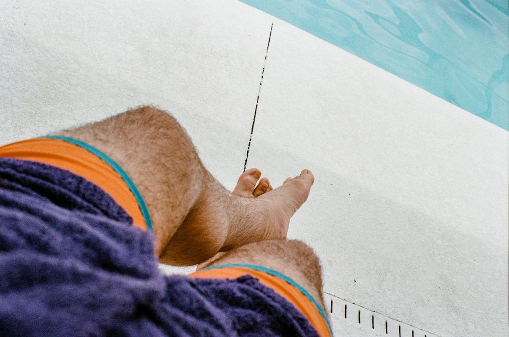 Close-up view of a flyer fishing rod with orange and navy blue sleeves visible against a white surface and blue background.