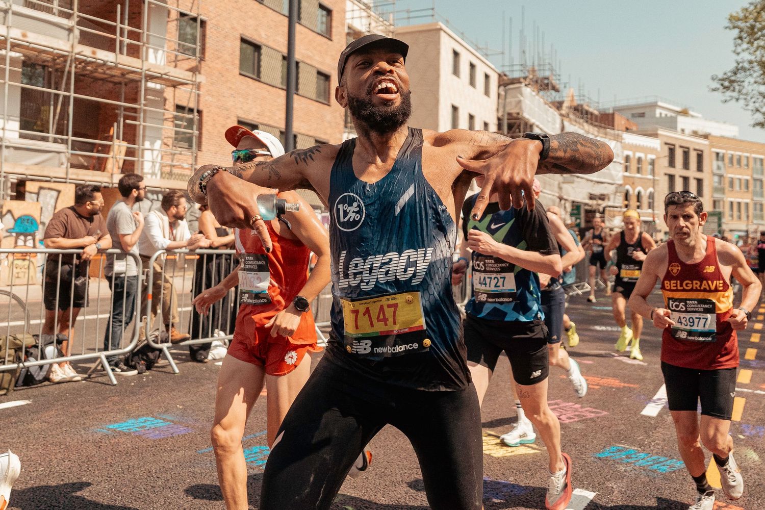 Marathon runner expressing joy and excitement during an urban race as spectators cheer from behind barriers.