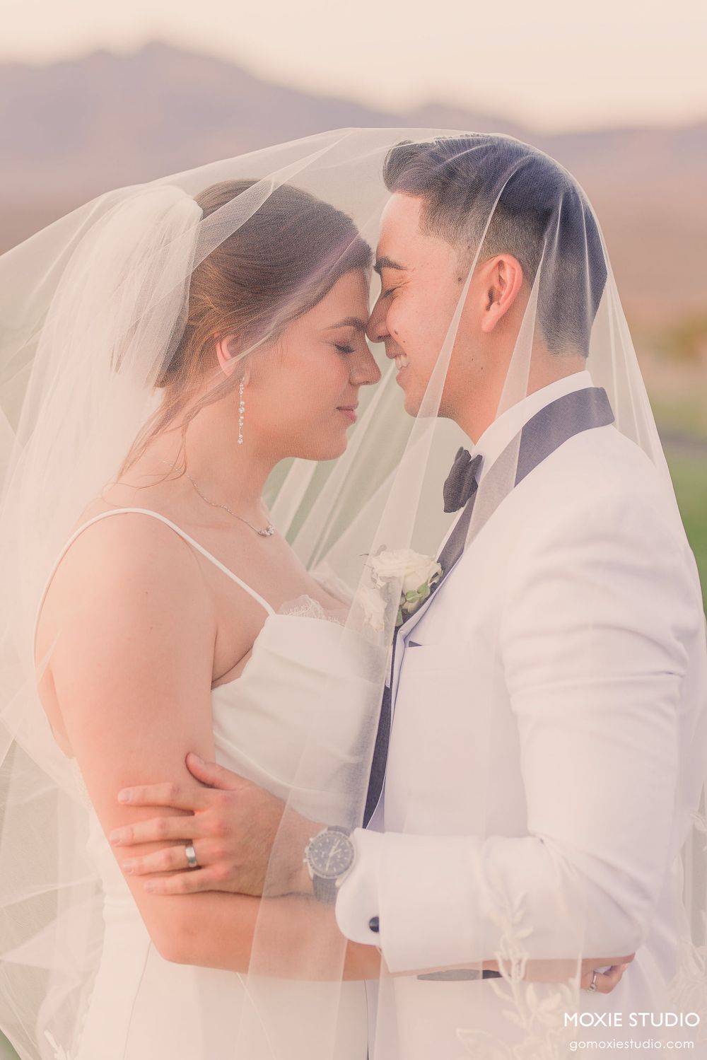 Five dreamy wedding portraits showing tender moments between a couple under a flowing white veil at golden hour.