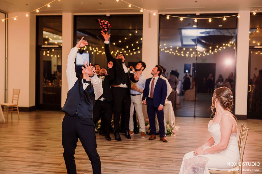 Wedding celebration with multiple dance moments captured under string lights in an indoor venue.