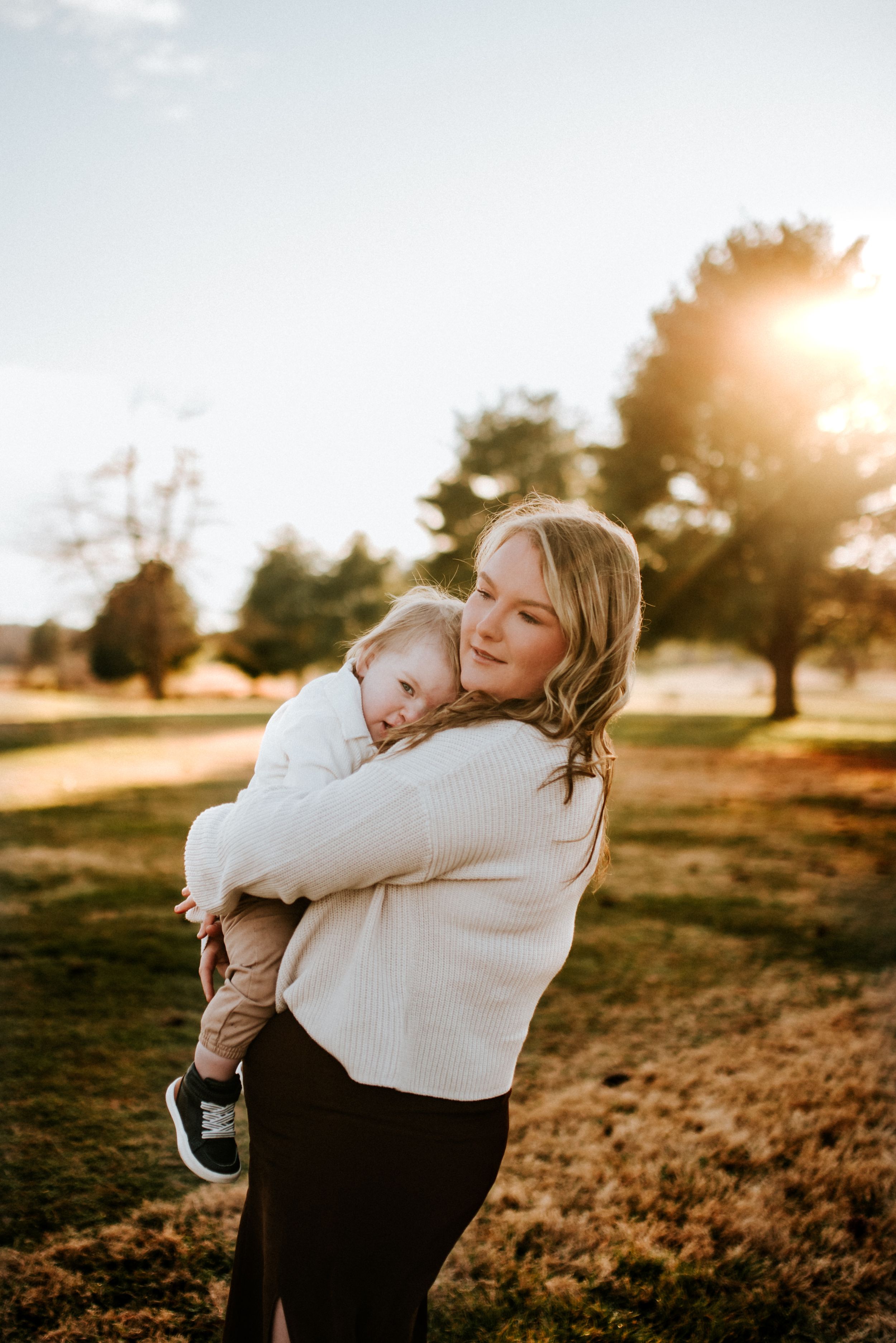 Mother comforting her 11 month old son with the sun shining through the trees in Sango, Tennessee.