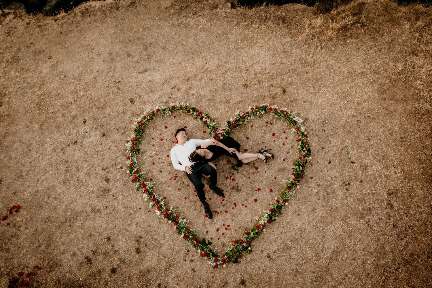 Chinese couple laying in a rose heart after they got engaged at Alki Beach