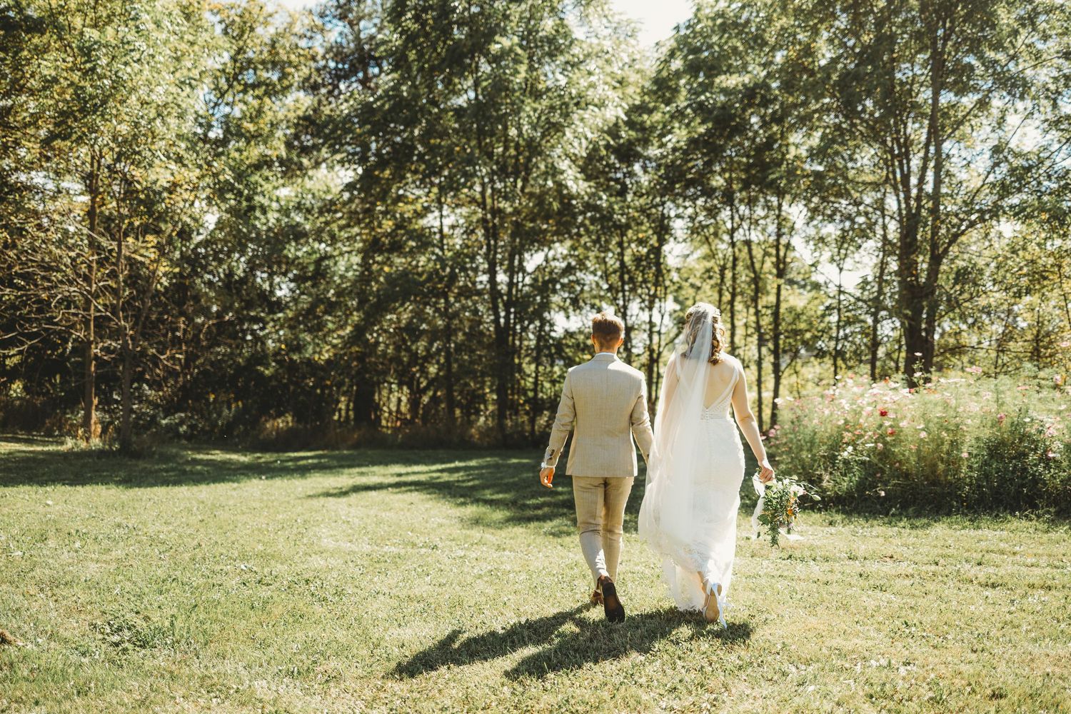 Bride and groom walking away in a field with flowers at 2gathermore in michigan