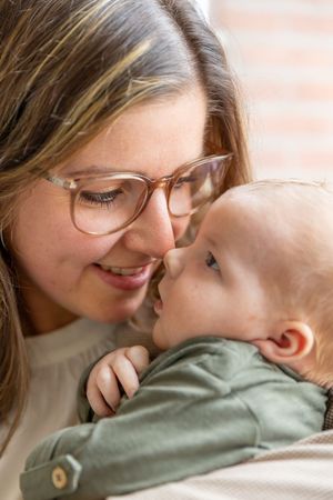 Moeder kijkend naar haar pasgeboren baby tijdens een newbornfotoshoot in Haarle