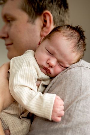 Pasgeboren baby slapend op de schouder van papa tijdens een newbornfotoshoot in Lemelerveld