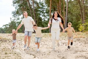 Gezin met drie jonge jongens. Rennen hand in hand. Zomers gekleed tijdens een gezinsshoot in Ommen