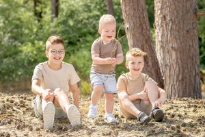 Drie broertjes, waarvan twee zittend en een staand. Zomers gekleed voor een gezinsshoot door Inge Muller Fotografie uit Lemelerveld.