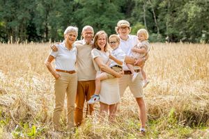 Familie staand in een korenveld tijdens een fotoshoot in Haarle. Alleen gekleed in wit / bruine kleding. Fotograaf Inge Muller.
