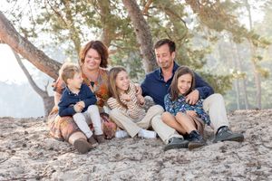 Gezin met drie meisjes, zittend en kietelend tijdens een fotoshoot op de Sahara bij Ommen