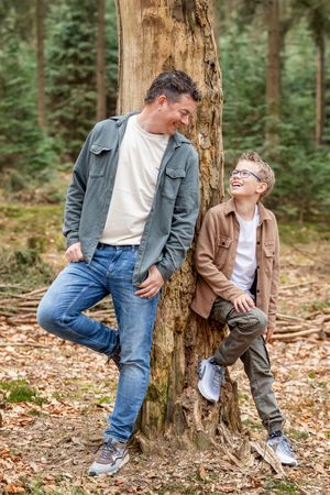 Vader en zoon staan met hun recht tegen een boom op de Lemelerberg en kijken elkaar aan