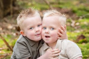 twee blonde broertjes met de wangen tegen elkaar aan