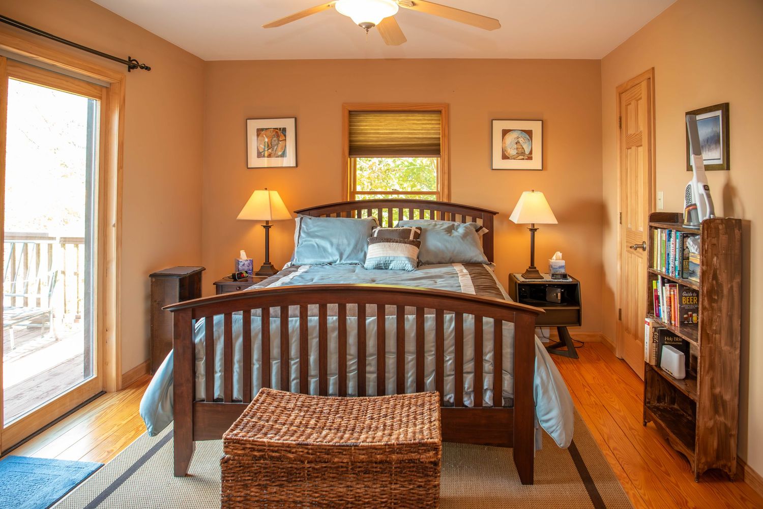 Panoramic view of a bedroom with tan walls, wooden furniture, and natural lighting from multiple windows.