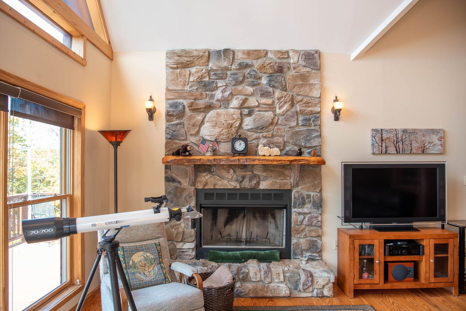 Rustic stone fireplace and entertainment center with vaulted ceilings in a modern living room.