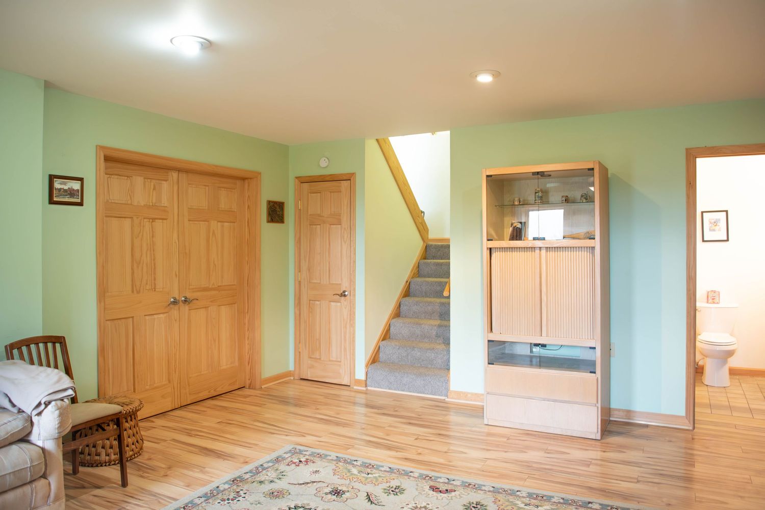 Interior photo showing multiple rooms of a house with mint green walls, hardwood floors and natural wood trim throughout.