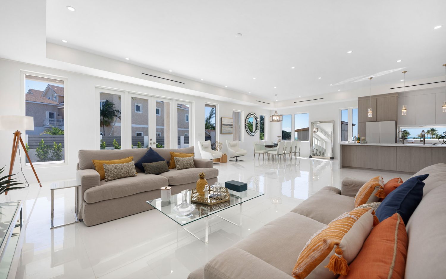 Modern luxury penthouse living room with white marble floors, gray sectional sofas and floor-to-ceiling windows.