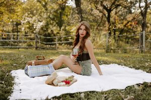 Elegant picnic arrangement with white blanket and vintage details in autumn park setting.