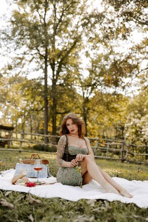Romantic picnic scene with wine glass and vintage accessories on white blanket.