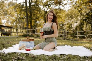 Autumn outdoor picnic scene with wine and basket on white blanket surrounded by fall foliage.