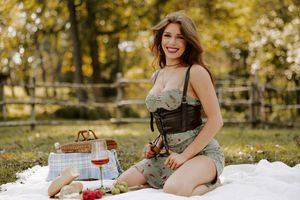 Outdoor autumn picnic with wine and basket set against golden fall foliage and rustic fence.