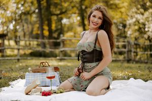 Rustic outdoor picnic with wine and basket arranged on white blanket during fall season.