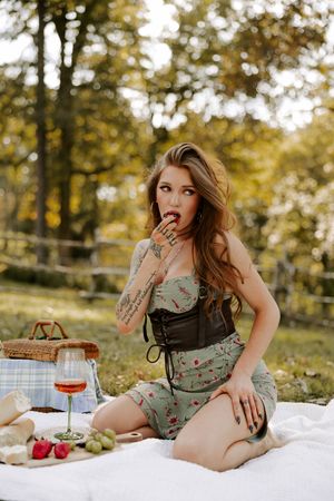 Romantic outdoor picnic with wine and blanket surrounded by fall trees.