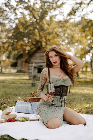 Casual outdoor picnic scene with wine glass and white blanket in park setting.