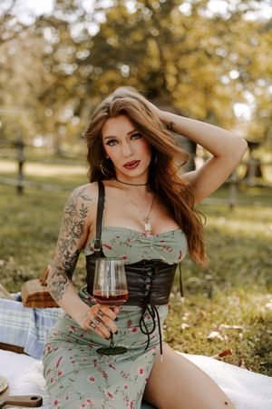 Autumn picnic scene with wine glass and vintage-inspired dress against fall foliage.
