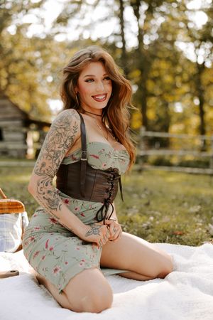 Summer picnic scene with model in mint dress and corset detail lounging on white blanket.