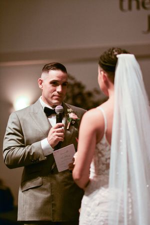 A wedding ceremony moment captured in moody lighting as vows are exchanged.