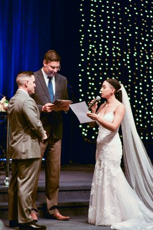 Wedding ceremony scene with twinkle light backdrop and blue curtains creating romantic ambiance.