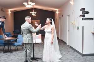 Wedding couple interaction in a hallway with chandelier lighting.