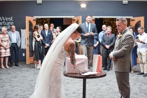 Wedding couple dances together in an indoor venue surrounded by guests.