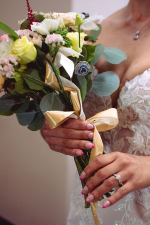 Close-up of a bridal bouquet with yellow and white flowers wrapped in gold ribbon.