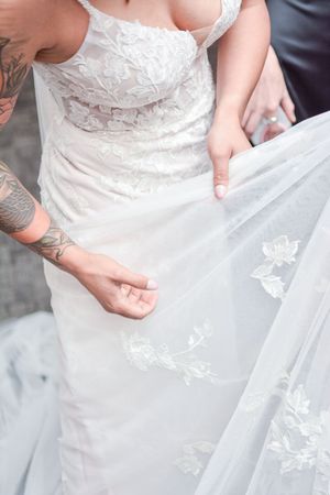 Close-up detail of white wedding dress with delicate butterfly lace pattern.