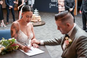 Couple signing wedding documents at ceremony table.